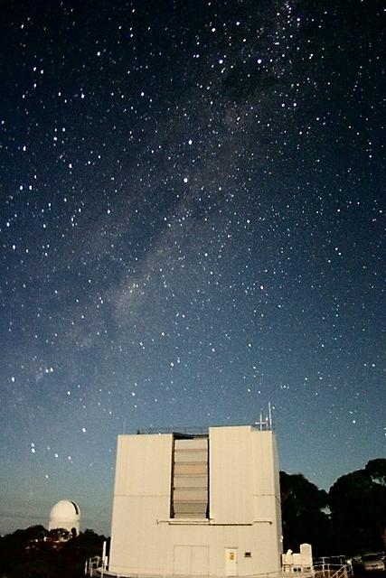 Looking south-east at the moonlit ANU 2.3m telescope building with the Anglo-Australian Telescope dome in the distance
