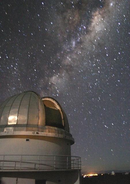 The Milky Way - and the lights of Coonabarabran - behind the dome of the ANU 40-inch telescope.
