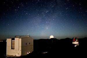 The moonlit ANU 2.3m telescope building, the Anglo-Australian Telescope dome in the distance